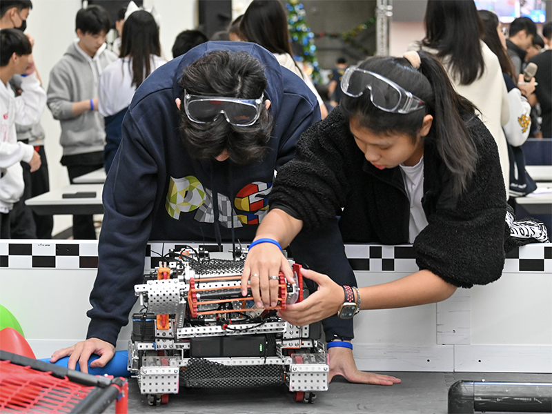 Students checking on their robots at the 2023 VEX Signature Event held in Pacific American School